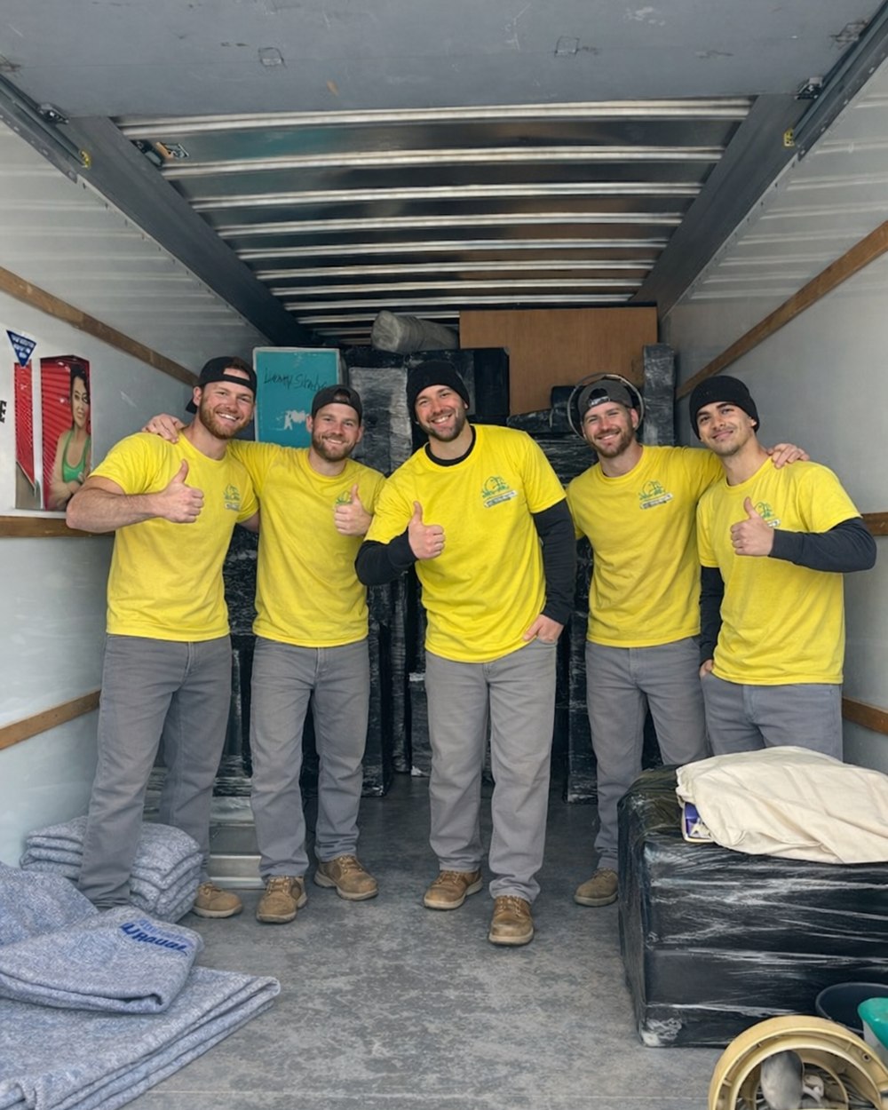 Five Hercules crew members giving a thumbs up inside a loaded moving truck